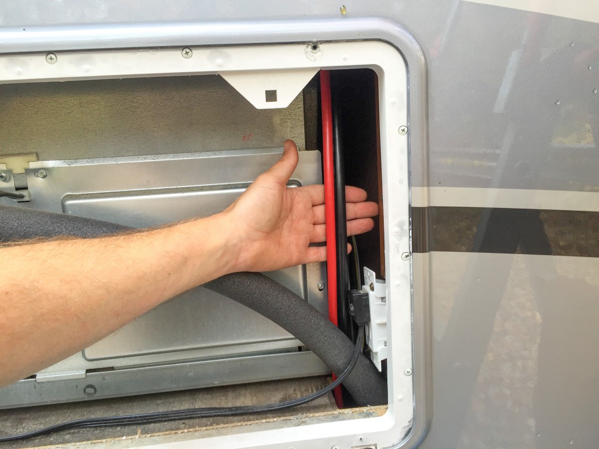 Grabbing the solar wire via the refrigerator access panel outside the RV.